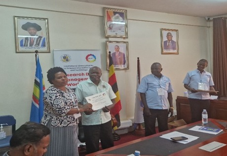 A black man in white T-shirt and a women in a decorated shirt are holding a certificate.